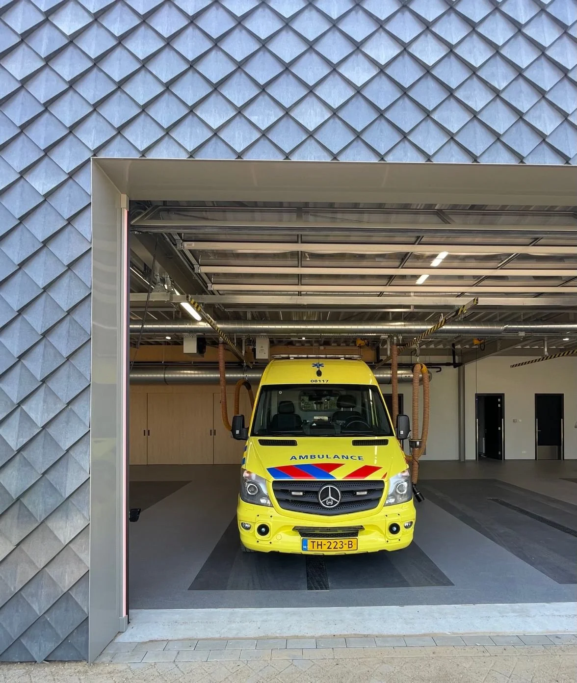 Bij het betreden van deze ruimte wordt direct de essentie van moderne utiliteit duidelijk. Een ambulance, omringd door onze grijze gevelbekledingstegels, symboliseert de naadloze integratie van functionaliteit en design. Dit beeld, waarbij onze tegel