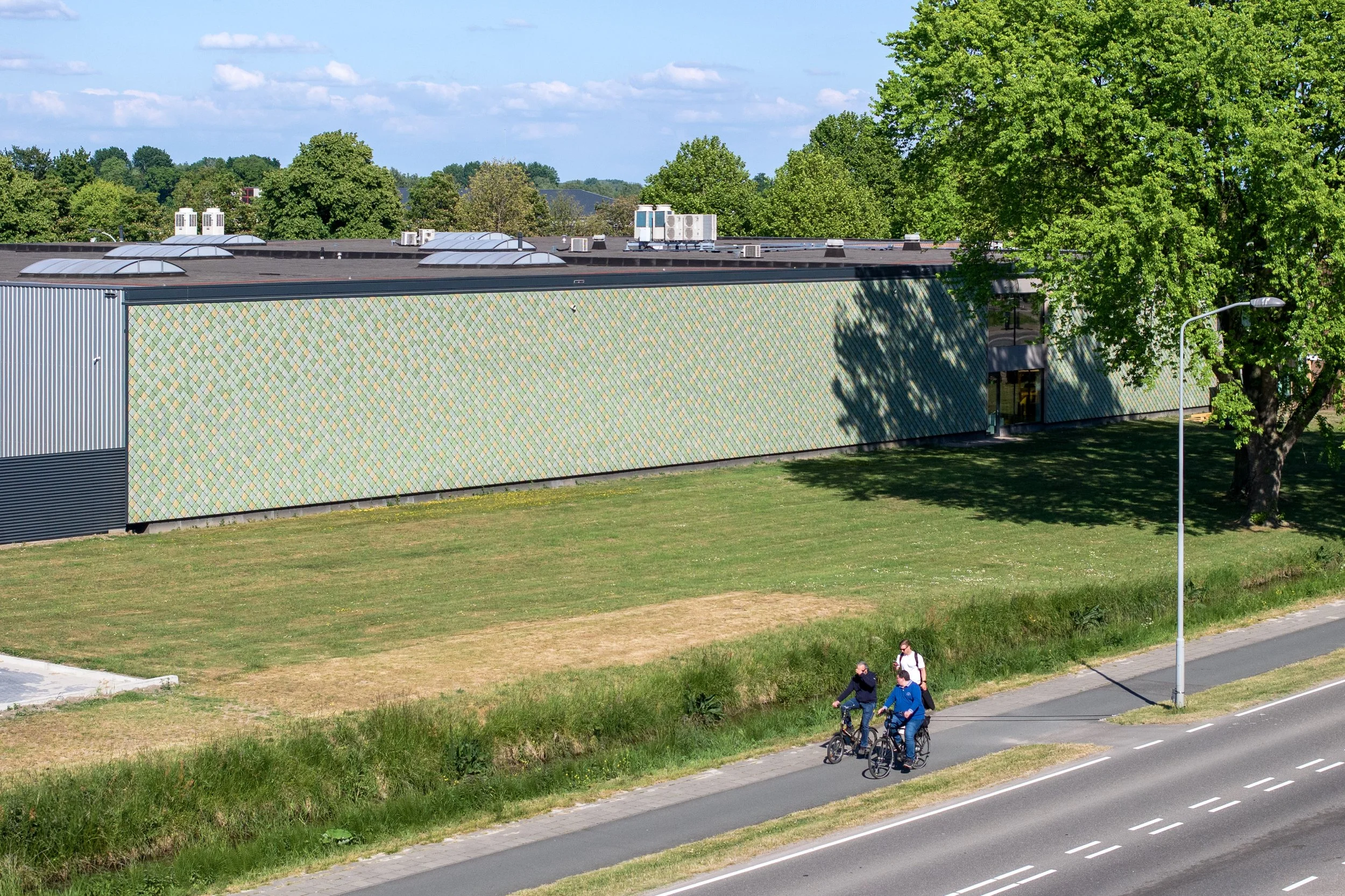 Drone view of Lensen Centre, Zaltbommel – side façade with Pretty Plastic First One tiles and adjacent road with cyclists.