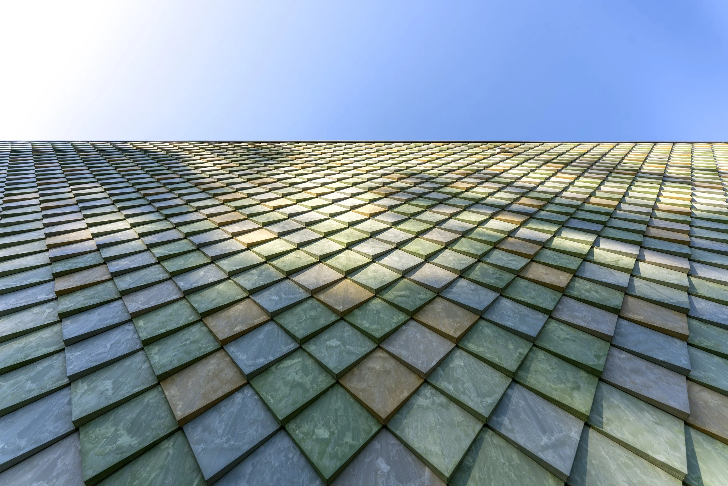 Upward detail view of the façade at Lensen Inspiration & Innovation Centre, Zaltbommel – showing the texture and layered rhythm of Pretty Plastic First One tiles.