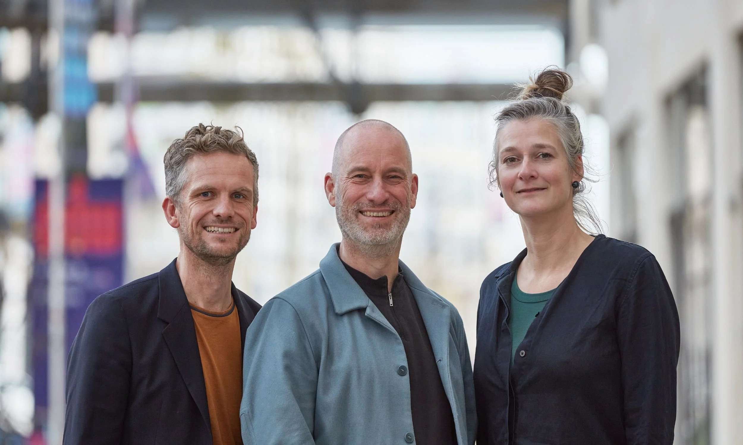 Our Founders smiling standing together in an indoor setting, with blurred shelves or displays in the background.