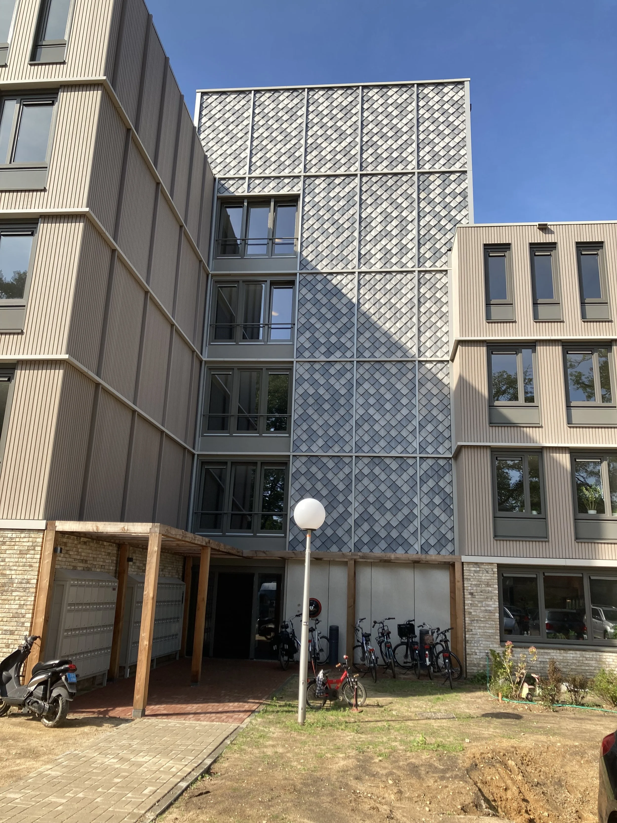 Bekijk De Vijverhof, een duurzaam meesterwerk in Berg en Dal. Gebouwd met First One tegels van Pretty Plastic, beslaat het 240m² en is ontworpen door INBO. De eerste foto toont het gebouw linksvoor, uitnodigend voor een verkenning van de perfecte sam
