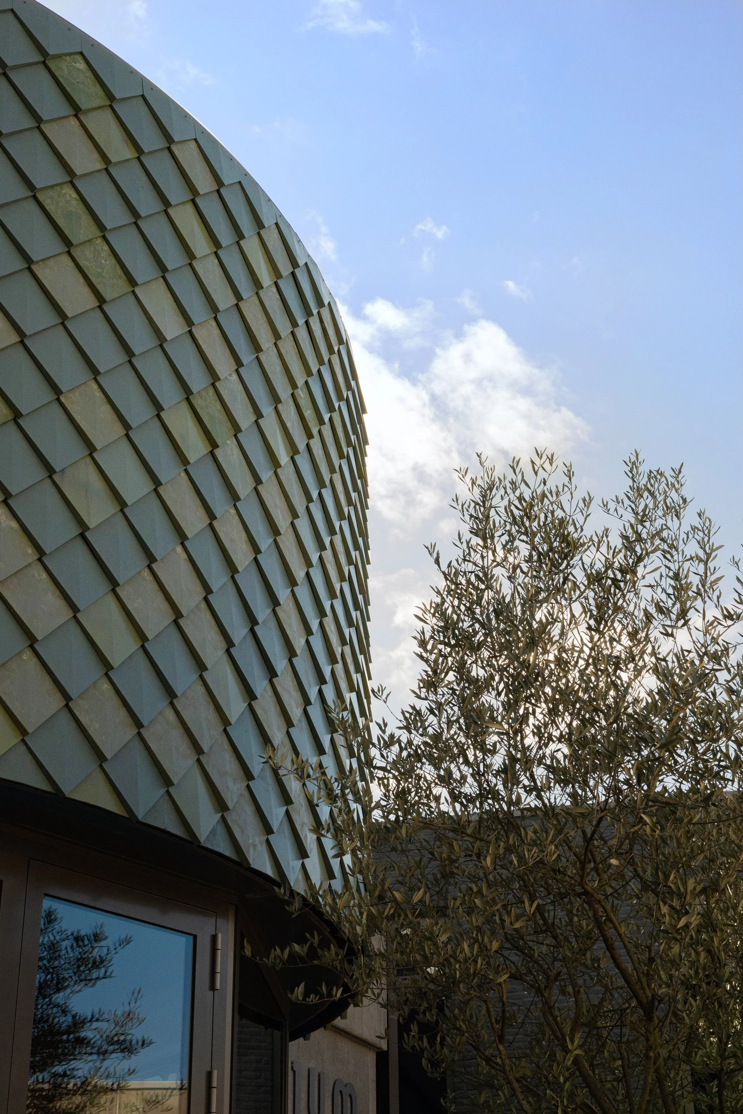 Pretty Plastic green tiles placed in a circel on a facade