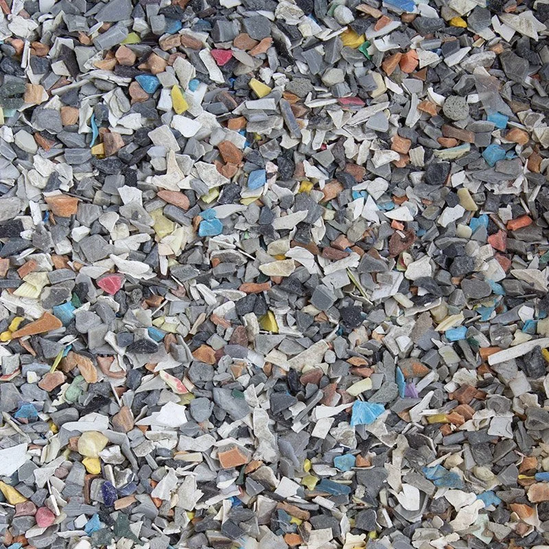 A close-up photo of a heap of mixed small rocks, gravel, and debris in various colors, including gray, white, brown, blue, yellow, and pink.