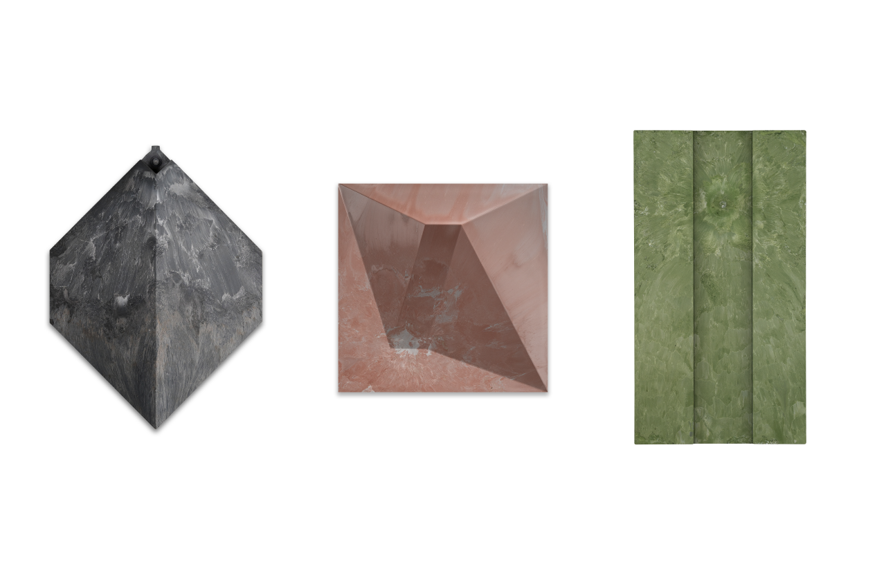 Three textured stone or marble tiles in a row: black and gray diamond-shaped tile on the left, reddish-pink pyramid-shaped tile in the middle, and green rectangular tile with a vertical pattern on the right.